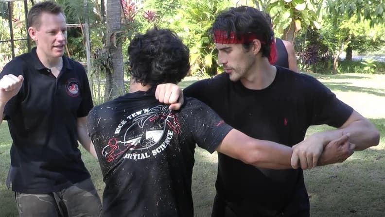 Rick Tew coaching two students through an arm technique outdoors
