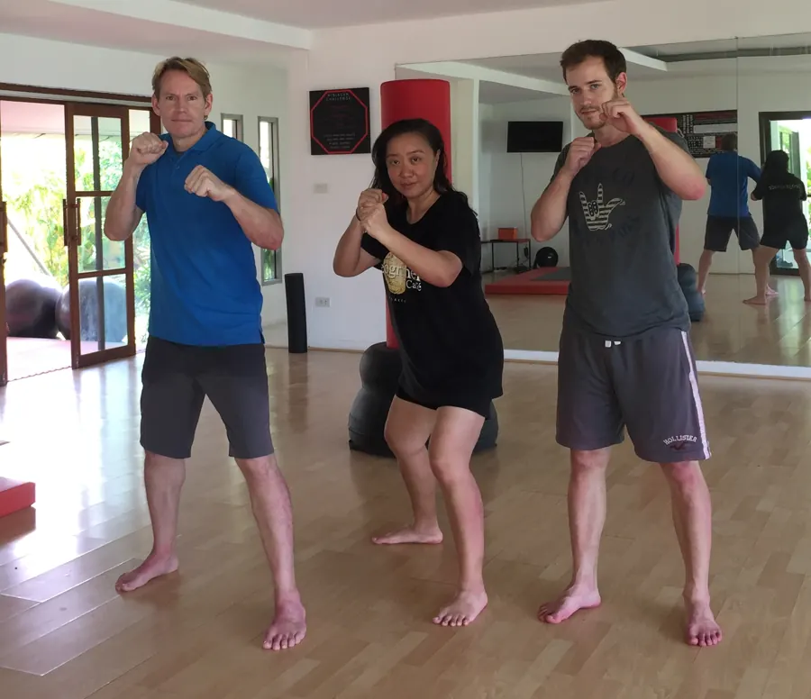 Rick Tew with a woman and a man in guard stance in a bright training hall