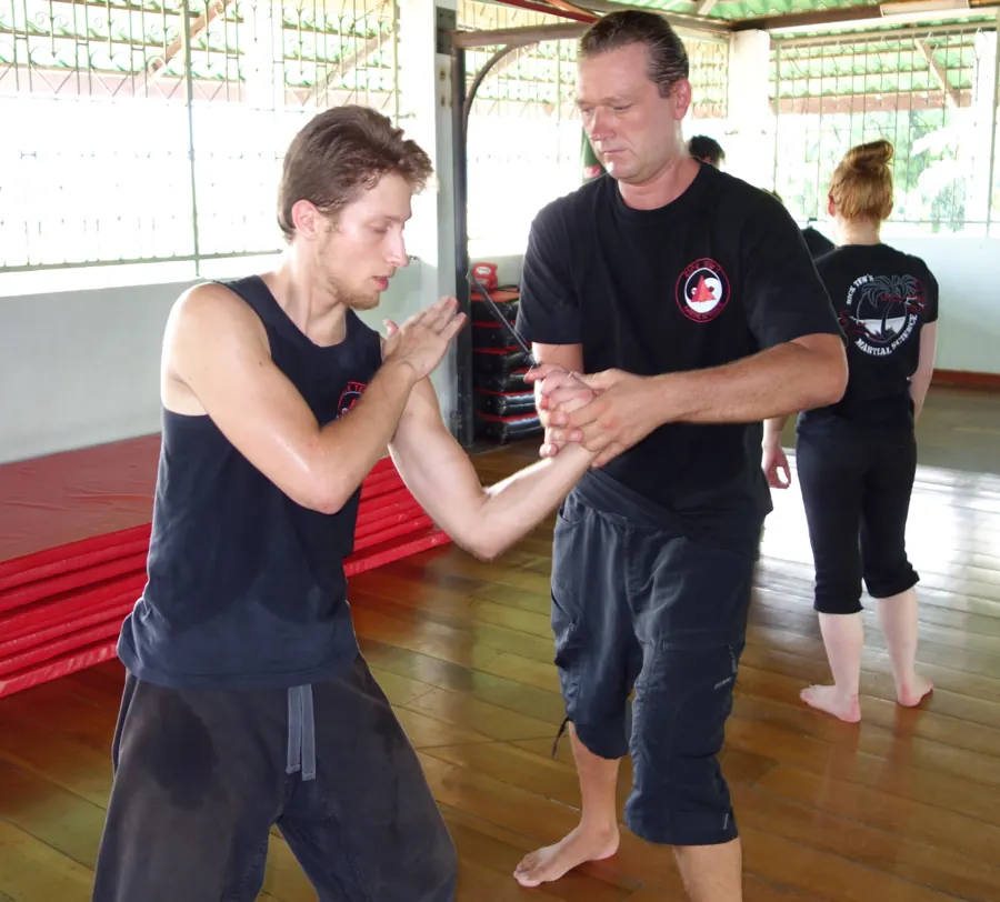 An instructor guides a student's wrist control while a woman waits her turn