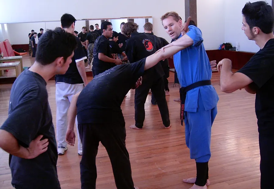 Rick Tew in a blue uniform shows an arm lock to a group of adults