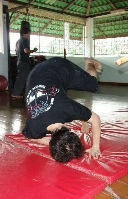 A student rolls forward on a red mat