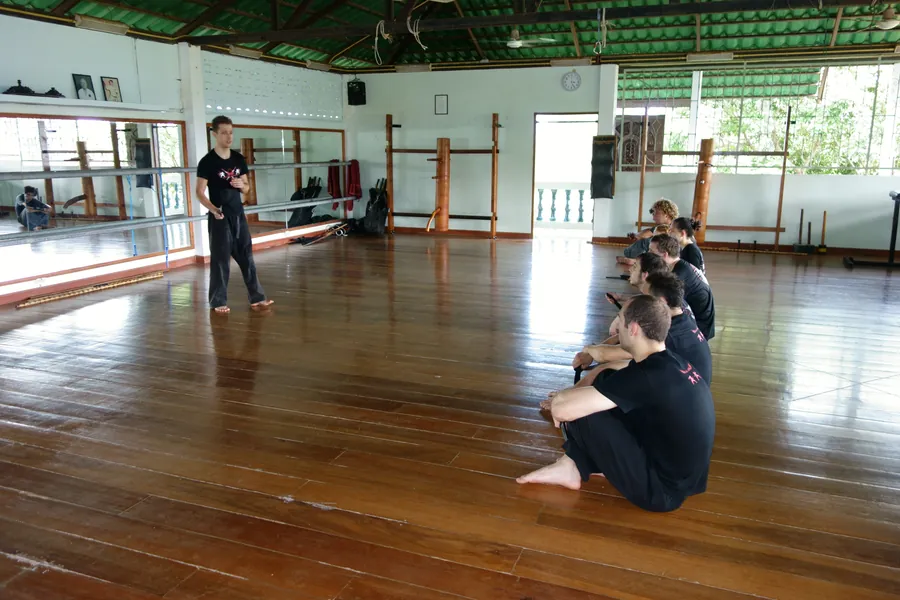 Students practice on the wooden floor of an open-air hall