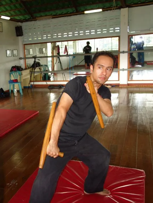 A student in a low stance with a staff