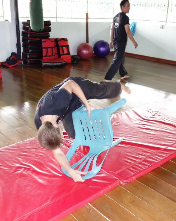 A woman rolls over a plastic chair onto the red mats