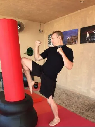 Rick Tew kicks a red standing bag