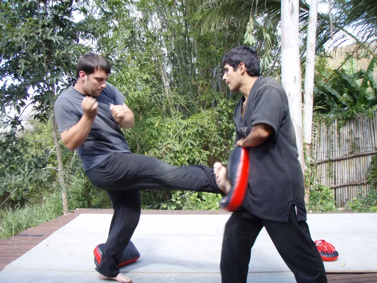 A student round-kicks a pad on an outdoor deck