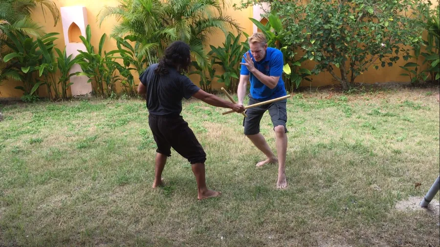 Two students drill a stick technique on a garden lawn