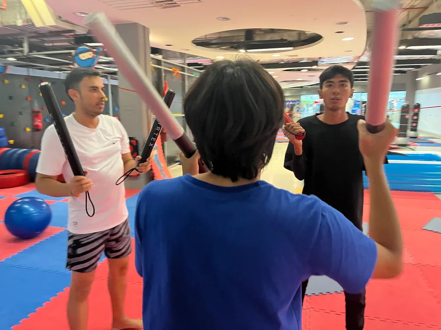 Students raise padded sticks in a drill