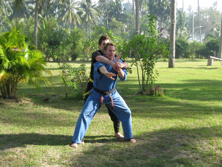 Rick Tew in a blue uniform breaks a hold from behind on a palm lawn