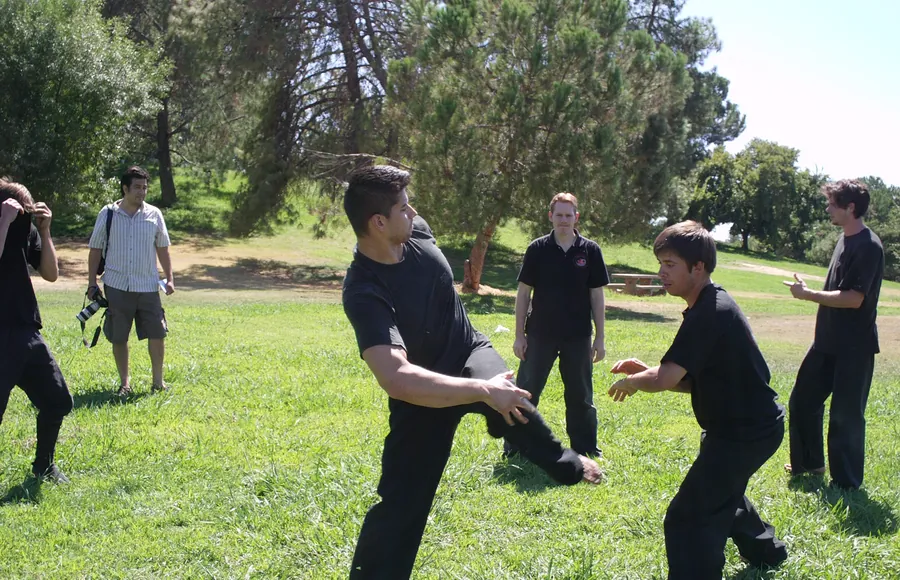 Pairs work a sweep drill on the grass in a park