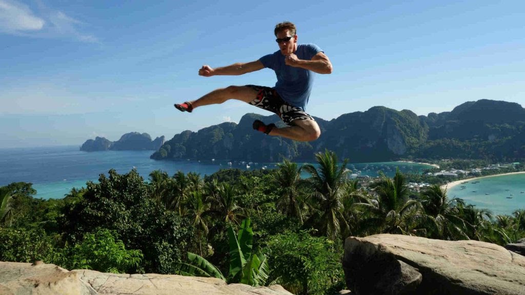 Rick Tew in a jump kick above a Thai island bay, years ago