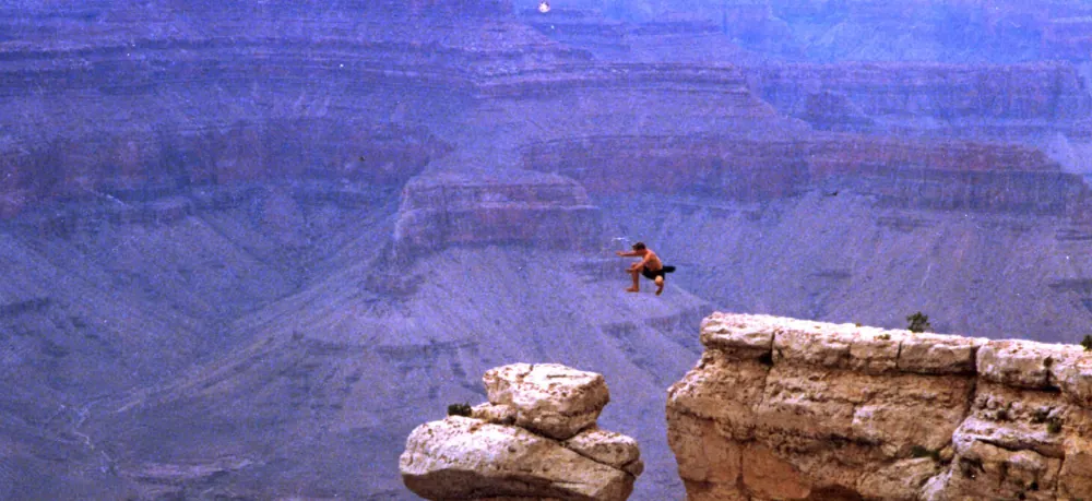 Rick Tew jumping from one rock tower to another at the Grand Canyon