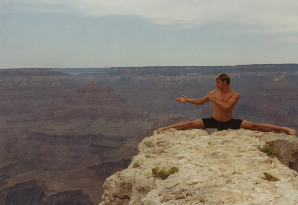 Rick Tew in the splits on a rock ledge at the Grand Canyon